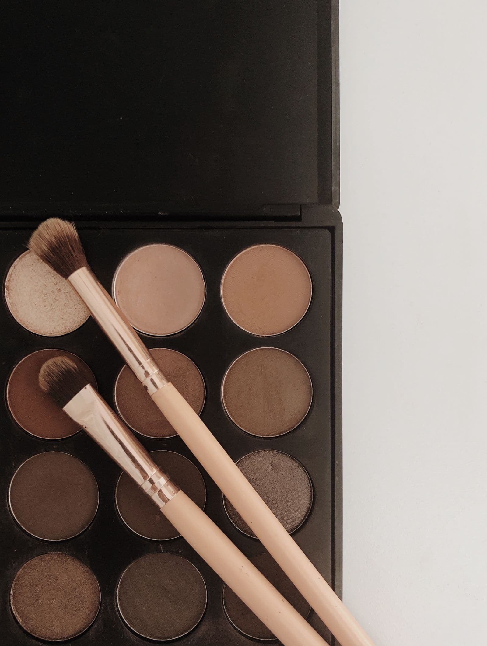 Makeup brushes resting on an eyeshadow palette.